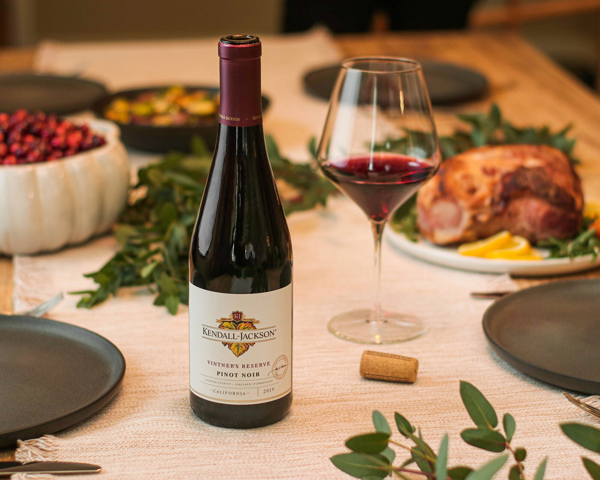Kendall-Jackson Pinot Noir wine bottle and a half full glass with a Thanksgiving spread