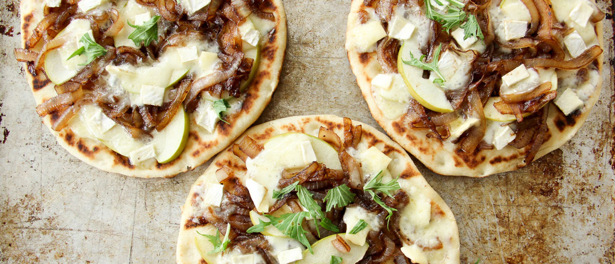 This Caramelized Onion, Apple and Brie Flatbread recipe is an ideal summer appetizer for an outdoor bbq or to enjoy as a personal entree for yourself.