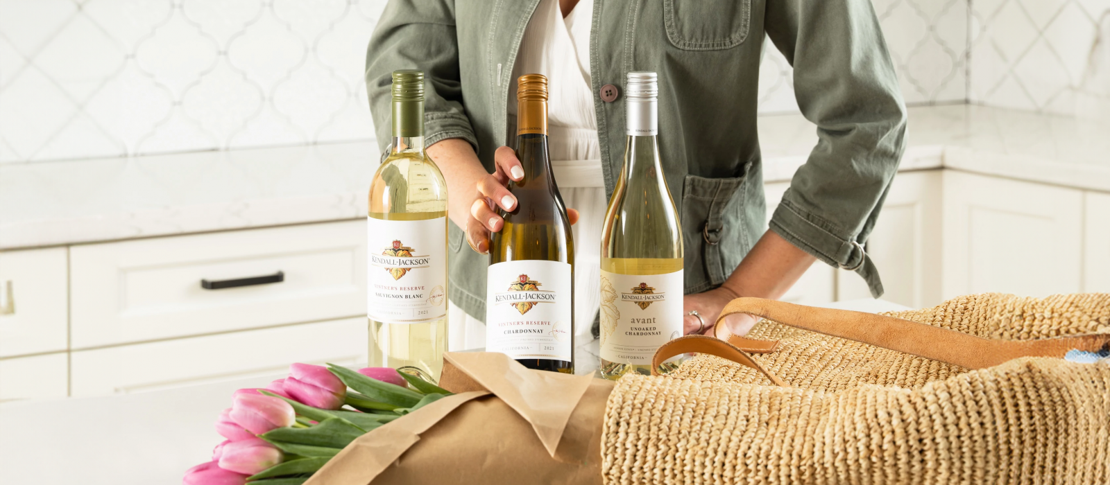 A millennial mom beams with joy in her modern farmhouse kitchen as she unwraps a Mother’s Day gift of fresh tulips and her favorite bottles of Kendall-Jackson wine.